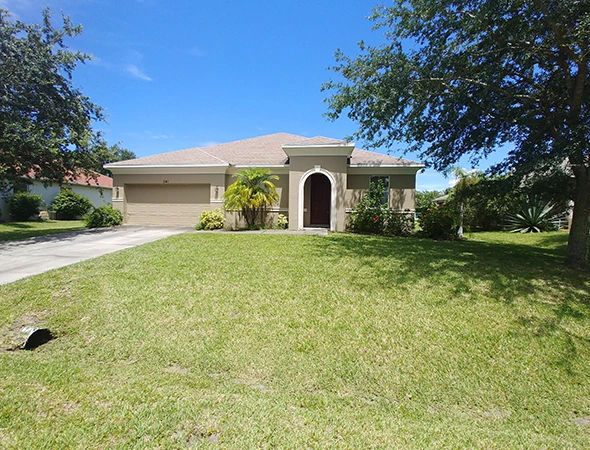 Affordable exterior house painting on a charming single-story home in Palm Bay, FL with fresh paint and green lawn.